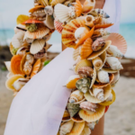 A woman wearing a colorful seashell lei on the beach.